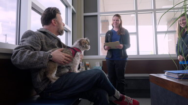 Man holding dog and vet tech holding clip board